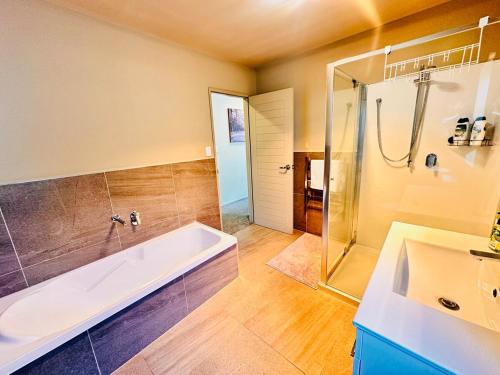 a bathroom with a tub and a shower and a sink at Modern Family Retreat Near Auckland City & Airport in Auckland
