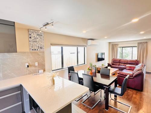 a kitchen and living room with a table and a couch at Modern Family Retreat Near Auckland City & Airport in Auckland