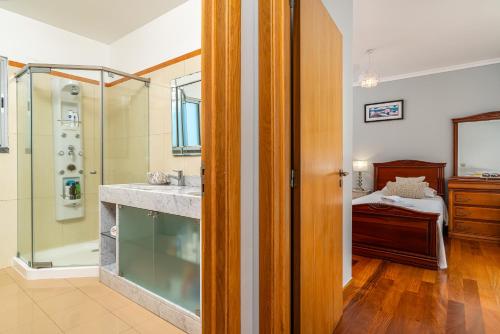 une salle de bain avec une douche et un lavabo et un lit dans l'établissement Villa Abreu - A Wonderful Ocean View, à Calheta