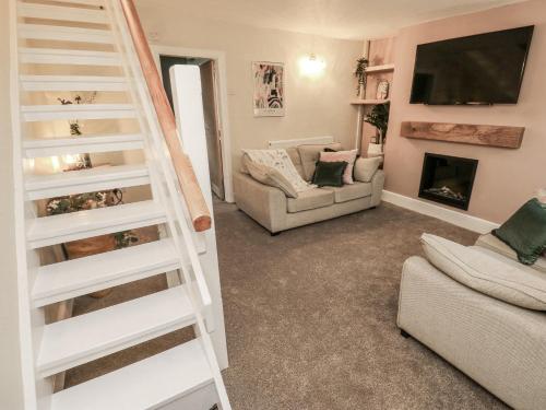 a living room with a staircase and a fireplace at Court Street Cottage in Oldham