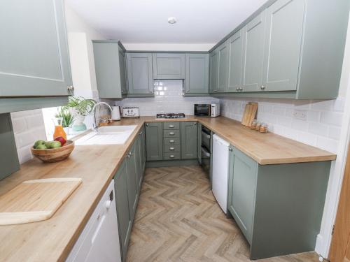 a kitchen with green cabinets and wooden counter tops at Court Street Cottage in Oldham