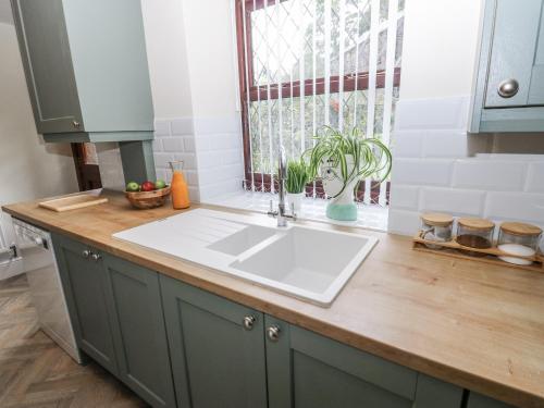 a kitchen counter with a sink and a window at Court Street Cottage in Saddleworth