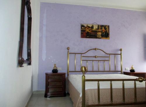a bedroom with a bed and a purple wall at Vacanza alla Chiesa Diruta in Grottole
