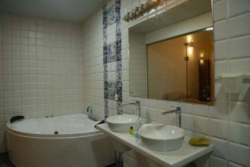 a bathroom with two sinks and a tub and a mirror at Hikka Resort in Hikkaduwa