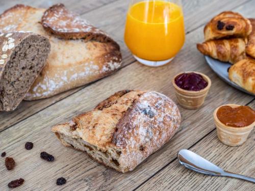 un tavolo in legno ricoperto di pane, succo d'arancia e succo d'arancia di ibis Styles Sceaux Paris Sud a Sceaux