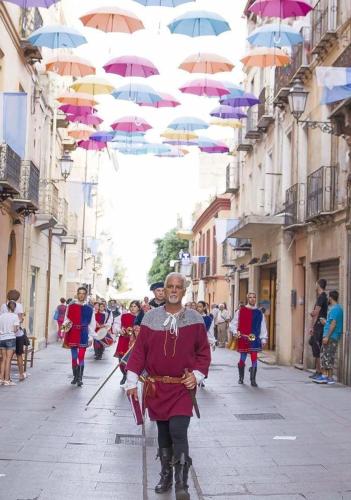 a group of people walking down a street with umbrellas at B&B Quintino Sella in Iglesias