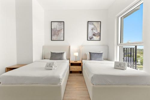 duas camas em um quarto branco com janela em FIRST CLASS 2BR Yas Island Living em Abu Dhabi