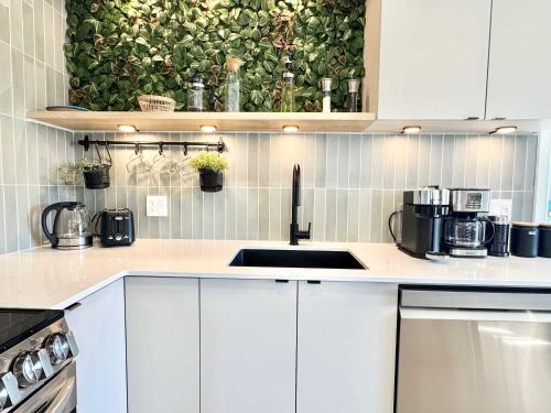 a kitchen with white cabinets and a green wall at L`Oasis Boheme - Hot tub - 2 Bedrooms - Free EVCharger in Boischâtel