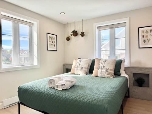a bedroom with a green bed with two windows at L`Oasis Boheme - Hot tub - 2 Bedrooms - Free EVCharger in Boischâtel