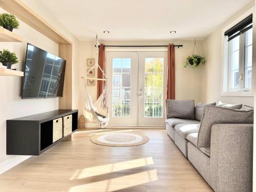 a living room with a couch and a tv at L`Oasis Boheme - Hot tub - 2 Bedrooms - Free EVCharger in Boischâtel