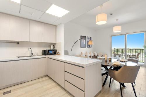 a kitchen with white cabinets and a table and a dining room at FIRST CLASS 2BR Yas Island Living in Abu Dhabi