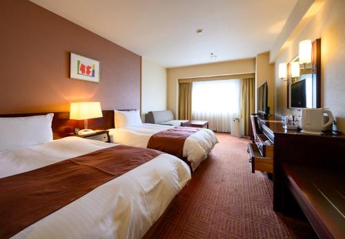 a hotel room with two beds and a television at Fukuyama New Castle Hotel in Fukuyama