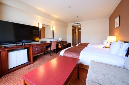 a hotel room with two beds and a flat screen tv at Fukuyama New Castle Hotel in Fukuyama