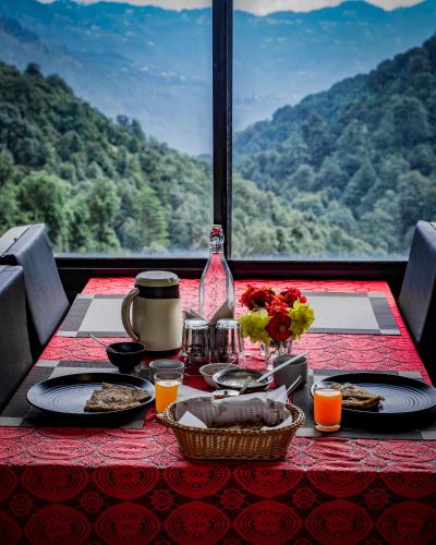 a table with food and a view of a mountain at Aurevelle Kastura Resort Kanatal - Mountain View Rooms in Kanatal