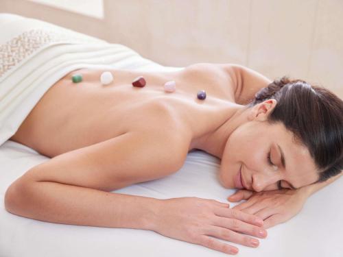 a woman laying on a bed with pills on her back at Fairmont Monte Carlo in Monte Carlo