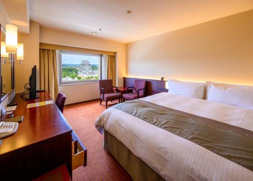 a hotel room with a bed and a desk and a window at Fukuyama New Castle Hotel in Fukuyama