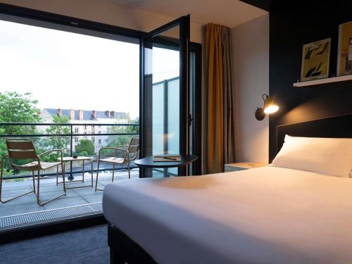 a hotel room with a bed and a balcony at ibis Styles Dreux Centre Gare in Dreux