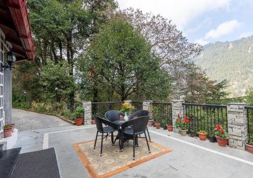 - une table et deux chaises sur une terrasse fleurie dans l'établissement Alaya Stays The Hive Cottage, à Nainital
