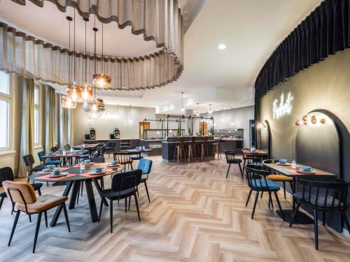a restaurant with tables and chairs and a kitchen at ibis Styles Bielefeld City in Bielefeld