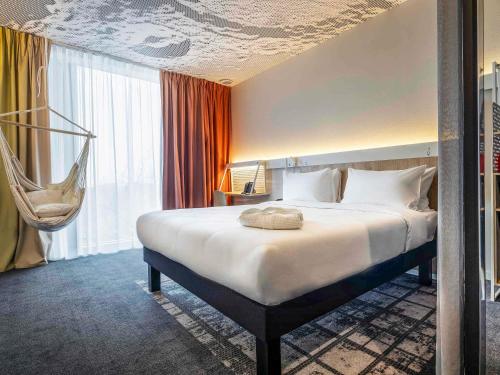 アルマトイにあるibis Almaty Jetisuのベッドとハンギングチェア付きのホテルルーム