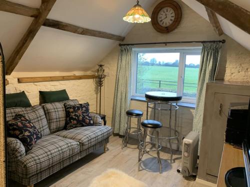 a living room with a couch and a table and a window at The Coach House at Stowford House in Babcary