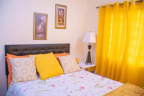a bedroom with a bed and a yellow curtain at Paradis des Palmiers 1 Gorgeous 2bedroom apartment in Belmont