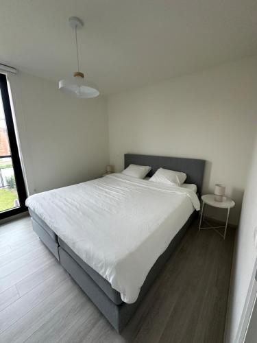 Un dormitorio blanco con una cama grande y una mesa. en Beaulivia Maaseik, en Maaseik
