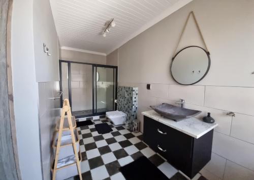 a bathroom with a sink and a mirror on a checkered floor at Stay at 64 Omeya in Windhoek
