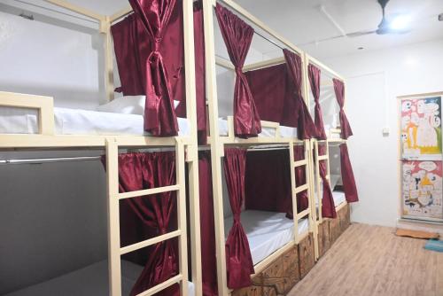 a room with three bunk beds with red curtains at Kashi Vibes Hostel in Varanasi