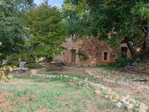 an old stone house with a table and trees at La Bergerie en Provence in Puimichel