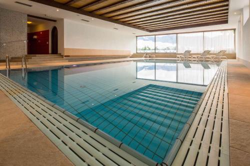 a large swimming pool with blue water in a building at Pension An Der Linde in Lagundo