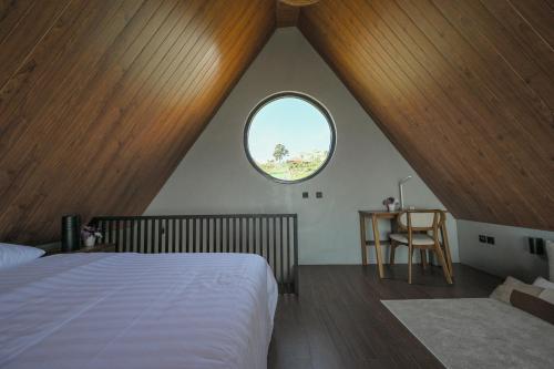 1 dormitorio con cama y ventana redonda en Le Nid du Clair de Lune, en Gitgit