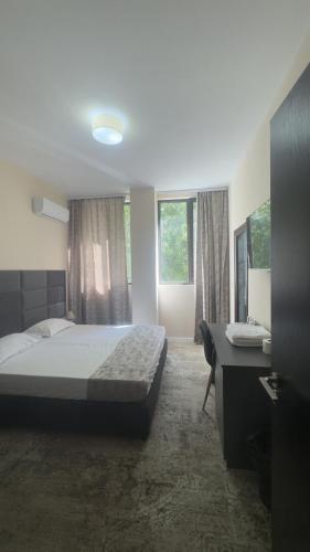 ein Schlafzimmer mit Bett, Schreibtisch und Fenstern in der Unterkunft Hotel Garden in Widin