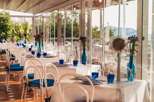 une rangée de tables avec des chaises blanches et des vases bleus dans l'établissement Gocce Di Capri Resort, à Massa Lubrense
