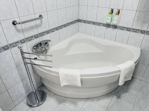 a white bath tub in a white tiled bathroom at Európa Apartman Mini in Békéscsaba