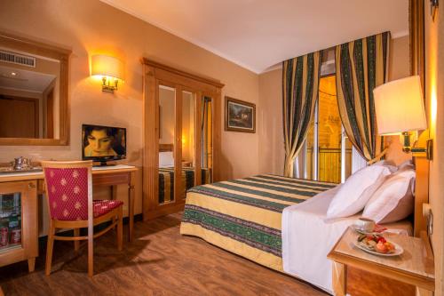 a hotel room with a bed and a desk and a sink at Colonna Hotel in Frascati