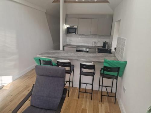 una cocina con barra con 4 sillas y un bar en Bright 2-Bed Flat with Free Parking near Whetstone, en New Barnet