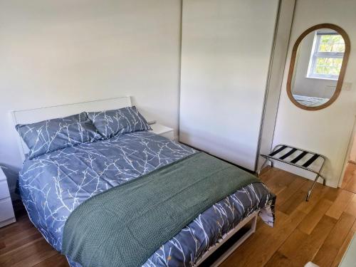 1 dormitorio con cama y espejo redondo en Bright 2-Bed Flat with Free Parking near Whetstone, en New Barnet