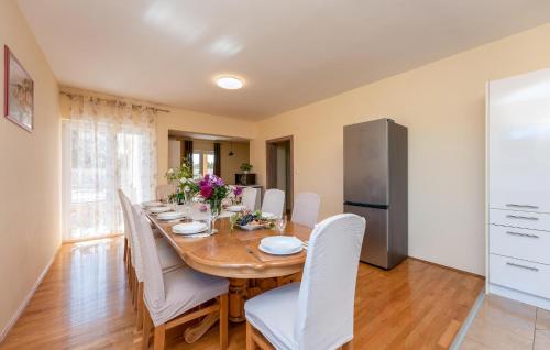 a dining room with a wooden table and white chairs at 5 Bedroom Cozy Home In Biograd Na Moru in Biograd na Moru