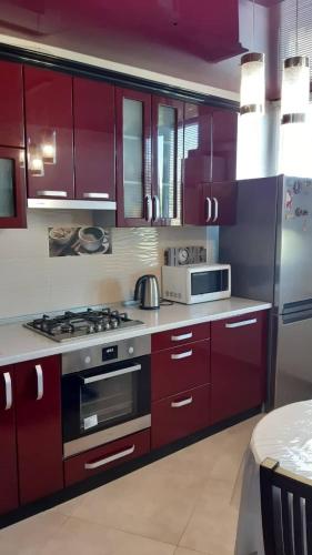 a kitchen with red cabinets and a stove top oven at Apart in Ivano-Frankivsʼk