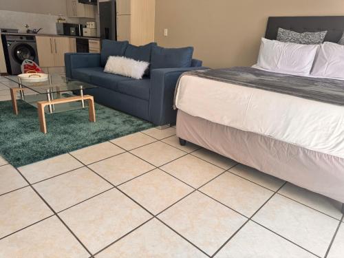 een slaapkamer met een bed, een bank en een tafel bij Eden Place in Vosburg