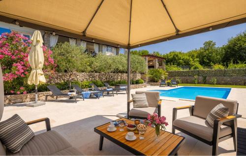 un patio con mesa, sombrilla y piscina en Villa Mia, en Sveti Ivan Dobrinjski