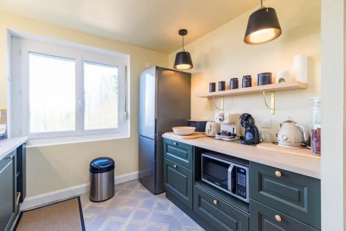 a kitchen with green cabinets and a black refrigerator at Maison familiale 8 personnes entre mer et campagne in Bégard