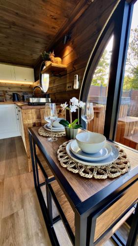 a table with plates and wine glasses on it in a kitchen at Luxury Tiny Home next to Belfry Golf Course Highland Cow