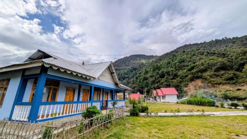 a blue house in front of a mountain at Accomoon River Side Cottages in Dirang Dzong