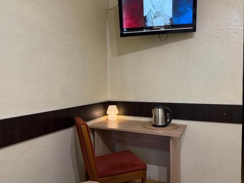 a small table with a chair and a tv on the wall at Home Boutique Hotel in Chişinău