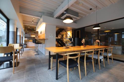 a dining room with a large wooden table and chairs at E10Hostel in Tokyo