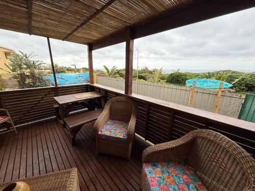a balcony with chairs and a table and an umbrella at Wazos Beach Villa in Durban