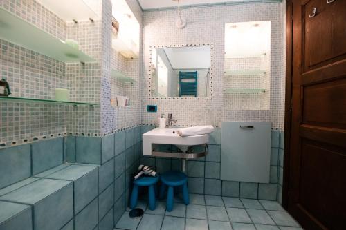 a bathroom with a sink and two blue stools at Blue Goose Apartment in Ronciglione