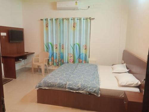 a bedroom with a bed and a desk and a television at SringeriRooms in Sringeri